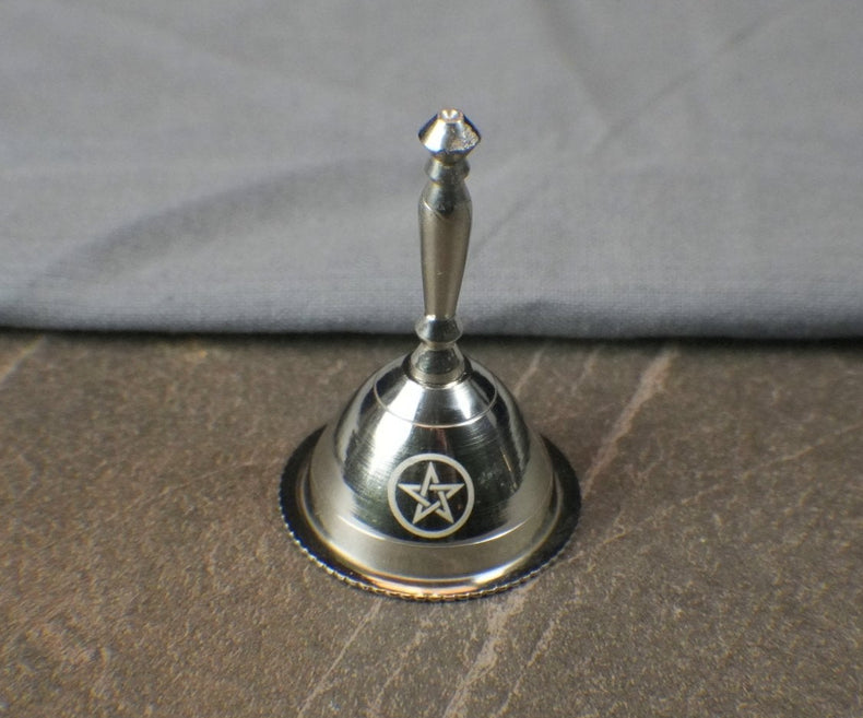 Silver bell with star design on a textured surface