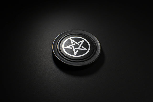 Black circular object with a white pentagram symbol on a stone surface