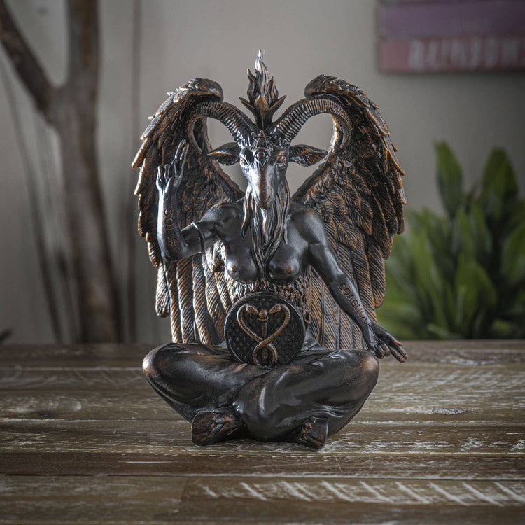 Statue of a winged creature with a heart symbol on a wooden surface