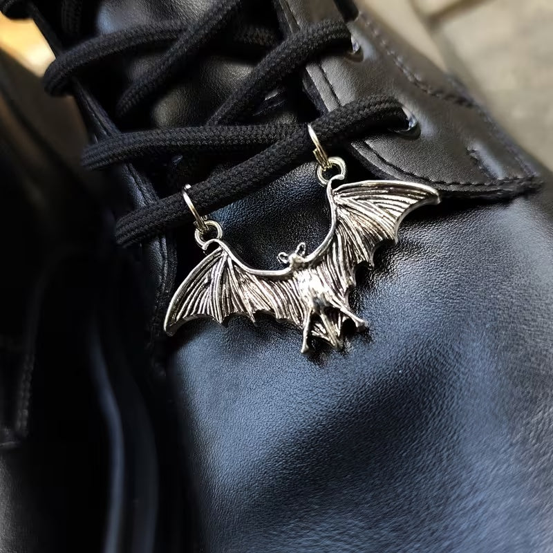 Silver-tone bat boot charm attached across black boot laces