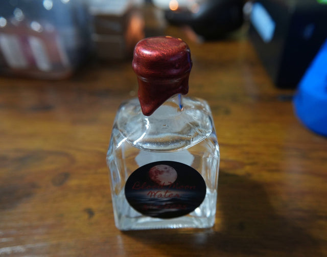 Small glass bottle with a red cap on a wooden surface