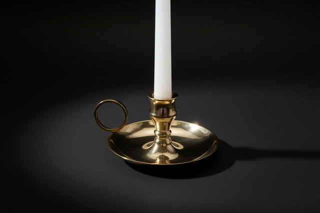 Gold candle holder with a white candle on a white background
