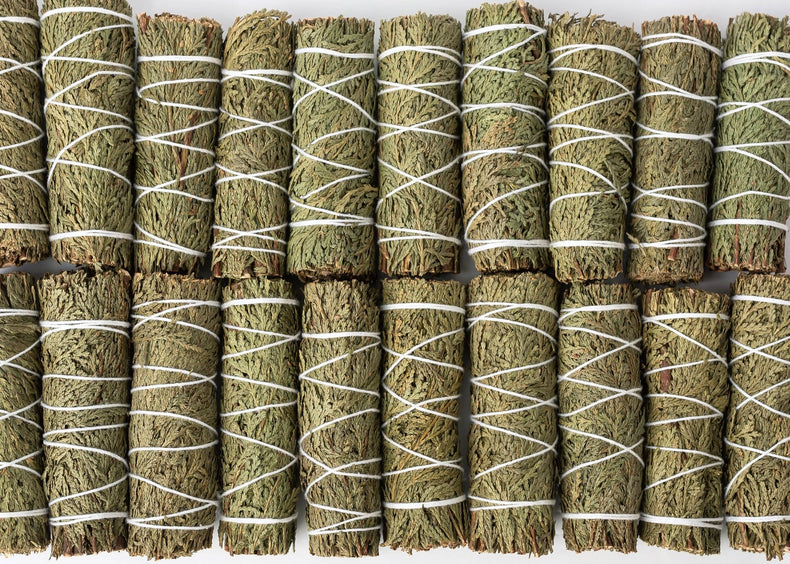 Multiple bundles of dried herbs tied with white string on a white background