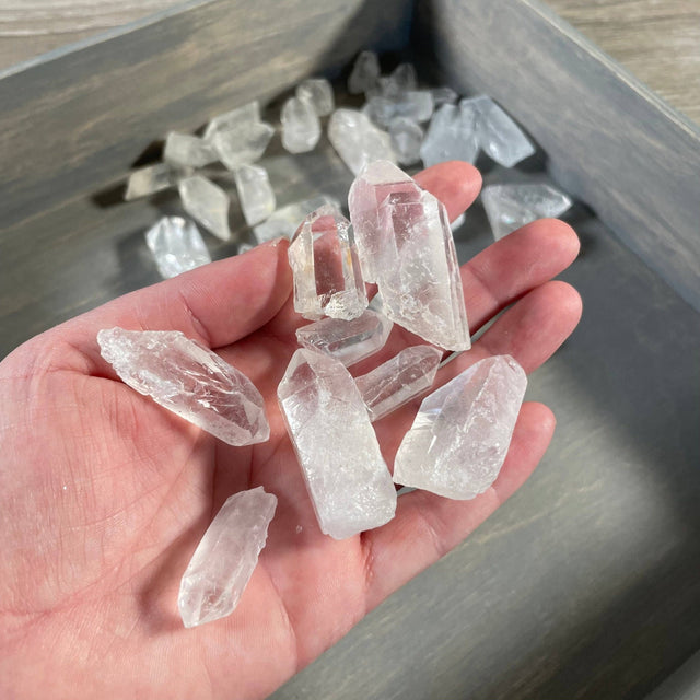 Hand holding clear crystal points with a wooden surface in the background