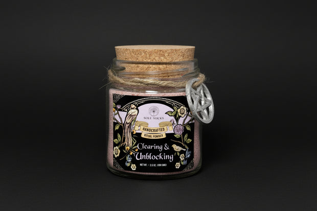 Glass jar with cork lid containing 'Clearing & Unblocking' ritual powder on a white background