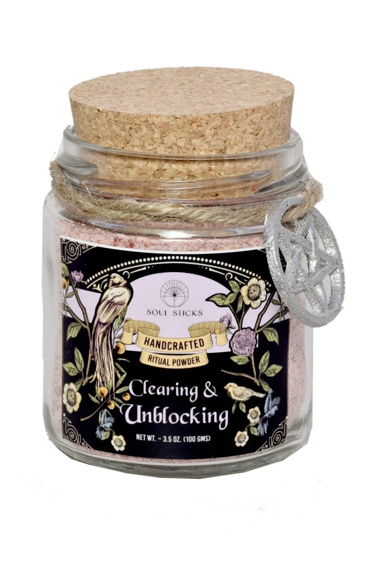 Glass jar with cork lid containing 'Clearing & Unblocking' ritual powder on a white background