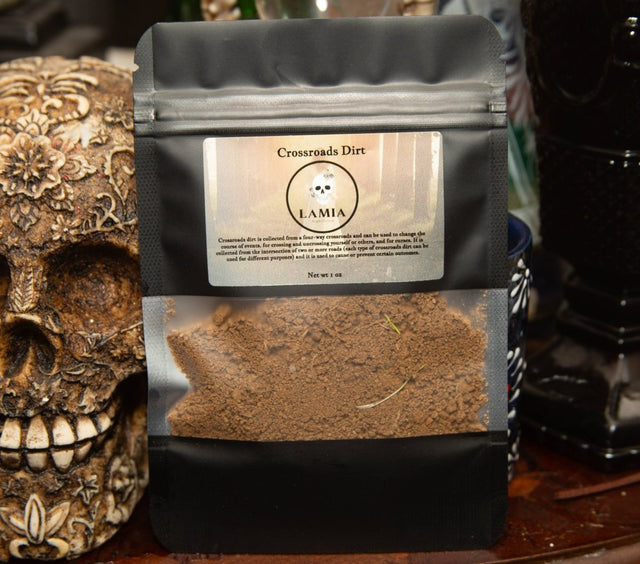 Black coffee bag labeled 'Crossroads Dirt' by LAMIA next to a decorative skull.
