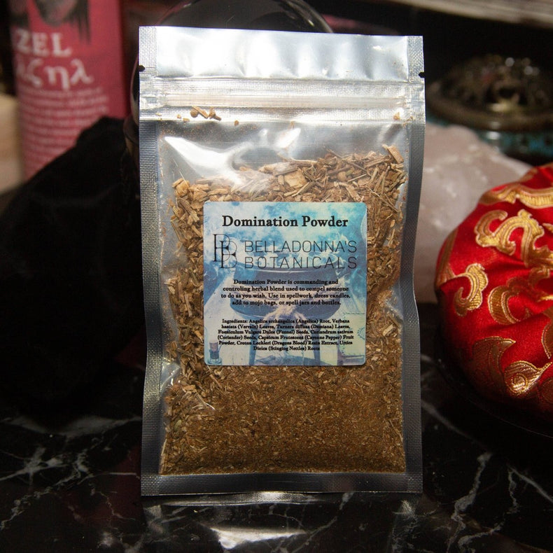 Packaged powder labeled 'Domination Powder' by Belladonna's Botanicals on a dark surface.
