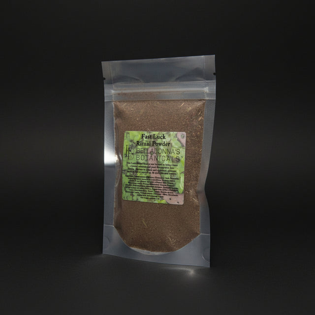 Packaged 'Fast Luck Ritual Powder' from Belladonna's Botanicals on a mystical background with stones and candles.