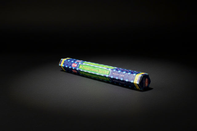 A pack of Frankincense & Myrrh incense sticks displayed horizontally on a wooden surface, with a colorful label visible.