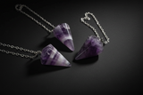 Purple pointed pendulum with chain shown in hand