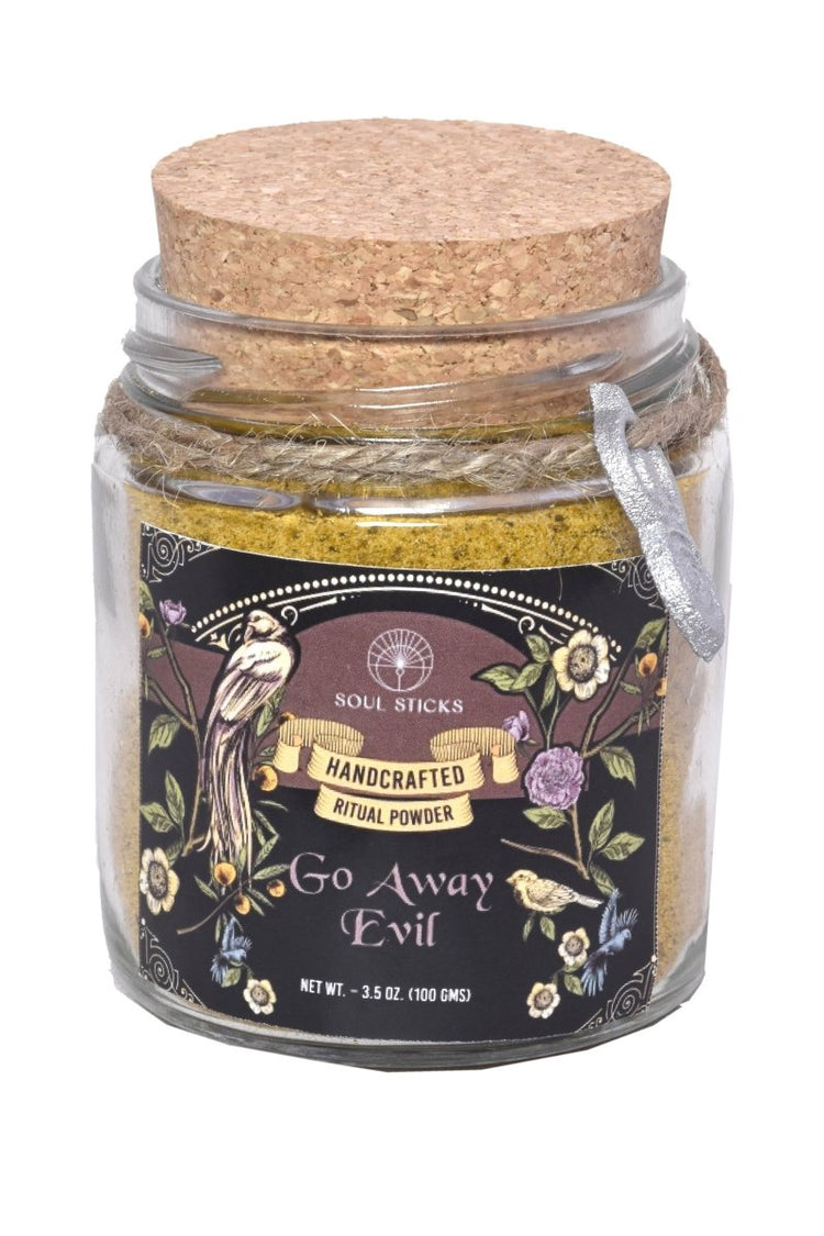 Jar of 'Go Away Evil' ritual powder with decorative label and cork lid on a white background