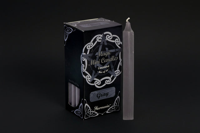 Gray candle next to its packaging with 'Harmonia' branding