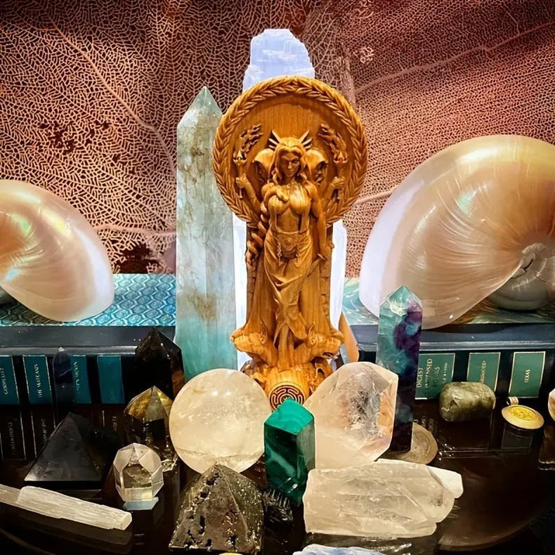 Collection of crystals and a resin Hecate statue on a textured surface