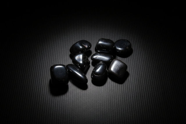 Hand holding shiny black stones on a neutral background