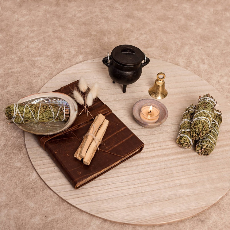 Spells and rituals items including a book, sage, and candle on a wooden surface.