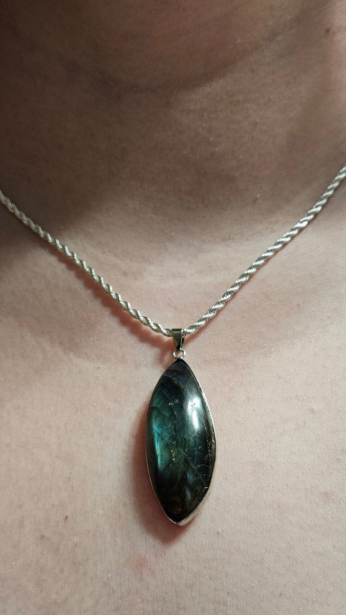 Necklace with a green pendant on a person's neck against a neutral background