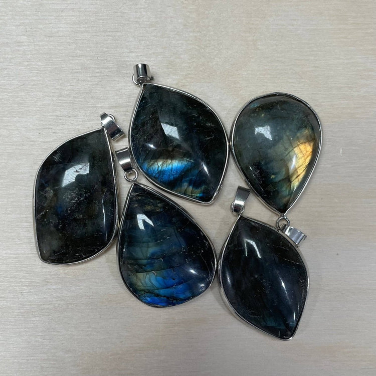 Set of four labradorite pendants with silver settings on a light gray background