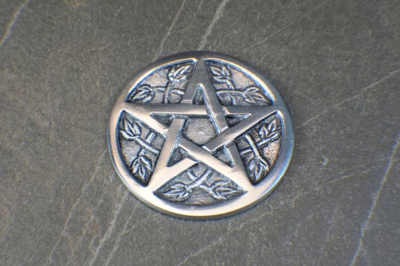 Silver pentagram pendant on a textured dark surface