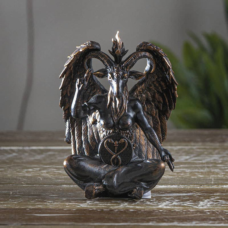 Statue of a winged creature with a heart symbol on a wooden surface