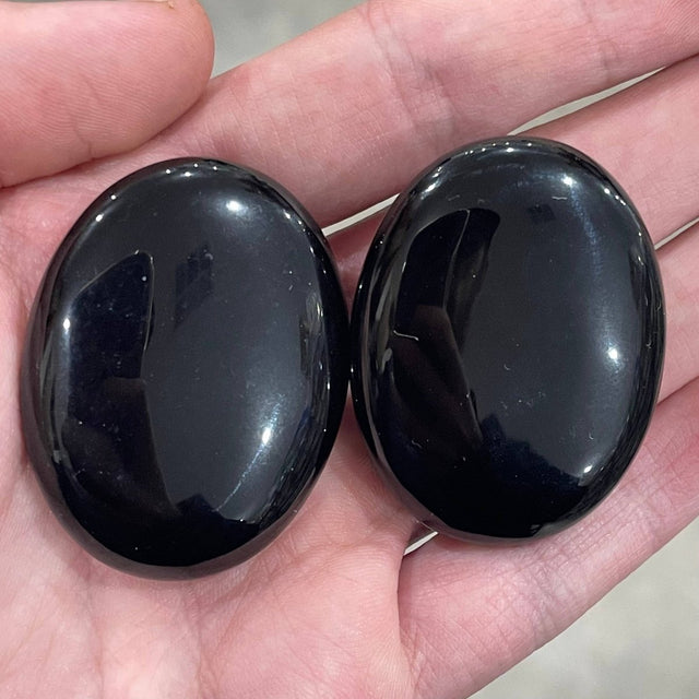 Two glossy black stones held in a hand