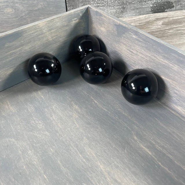 Four black spheres on a wooden surface