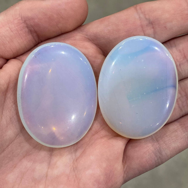 Two opal stones held in a hand, showcasing their iridescent surface.