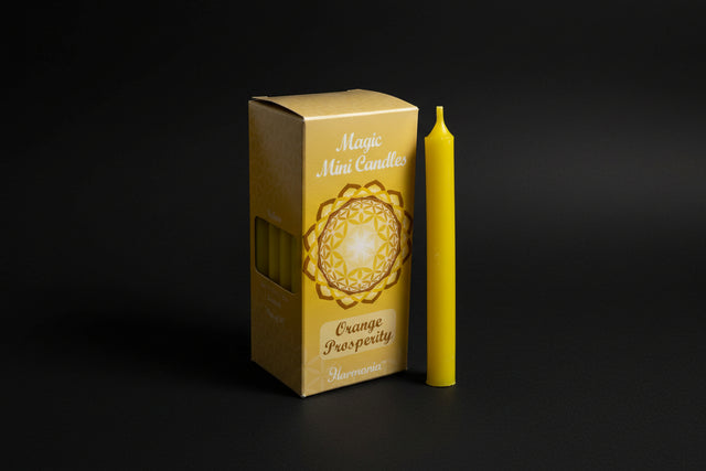 Yellow candle with packaging labeled 'Magic Mini Candles Orange Prosperity' by Harmonia on a white background.