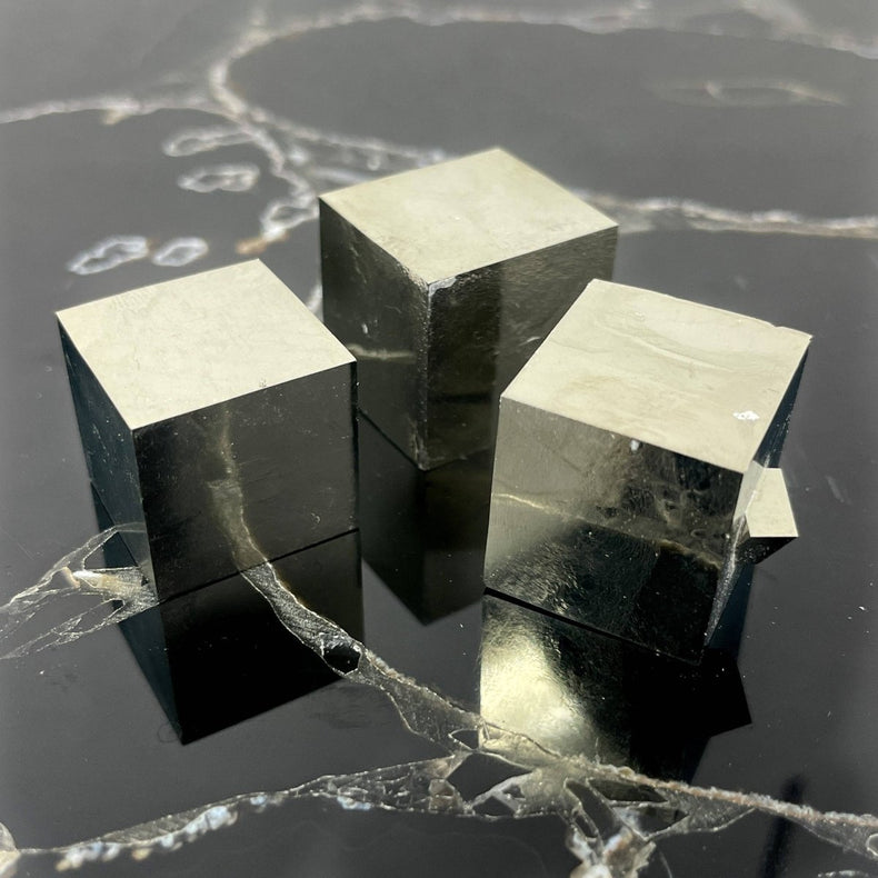 Three metallic cube blocks on a reflective black surface