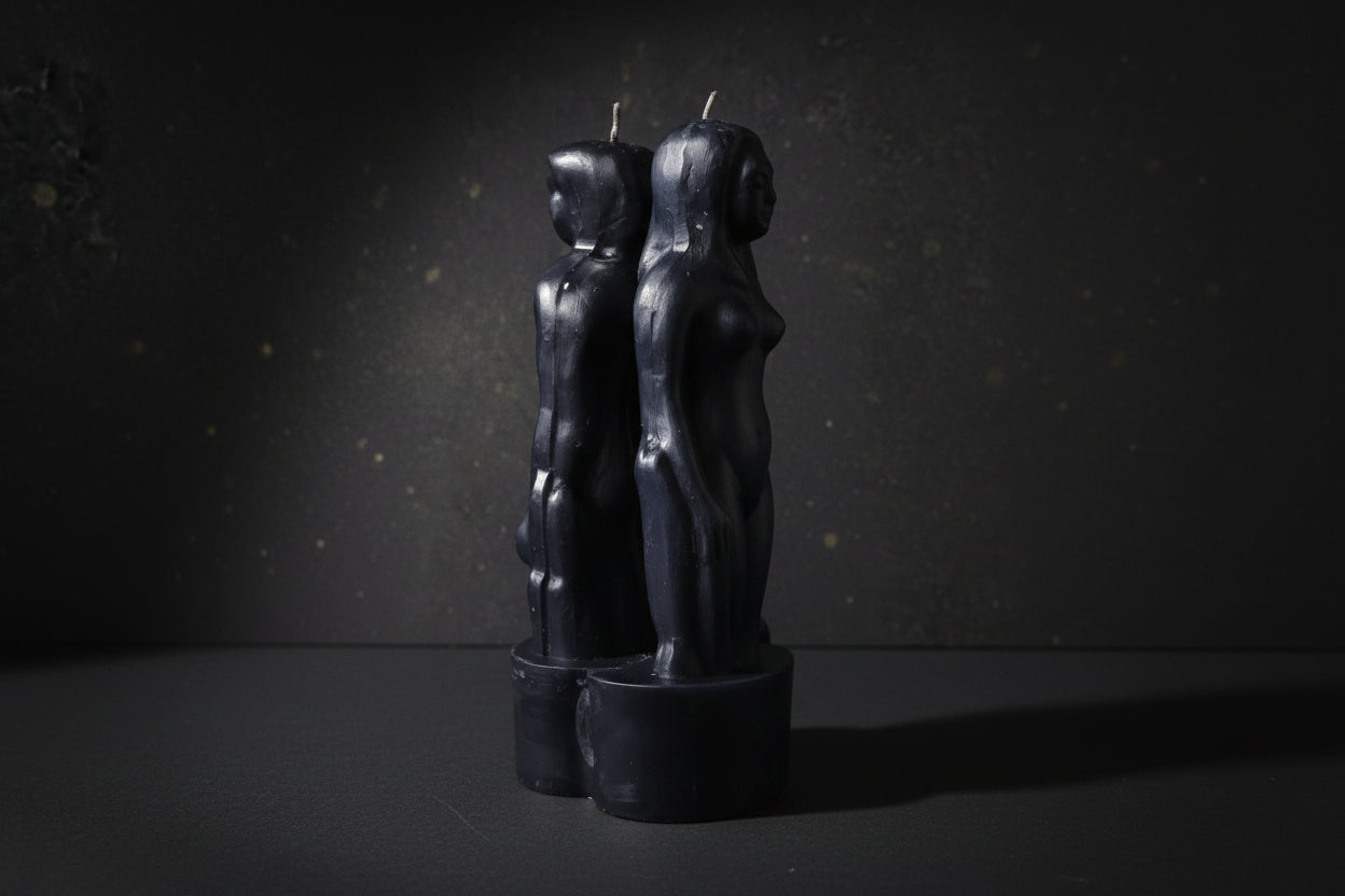 Black candle holders shaped like abstract human figures on a dark background with