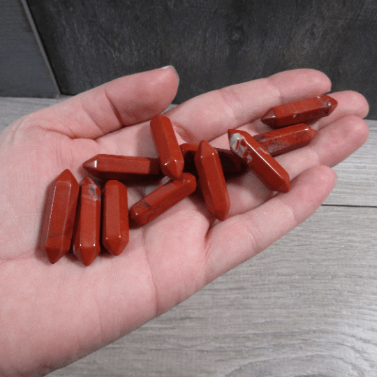 Hand holding red stones on a wooden surface
