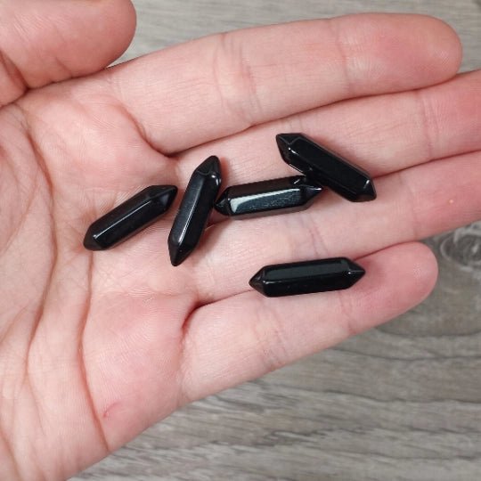 Black crystal points on a person's palm with a wooden surface background