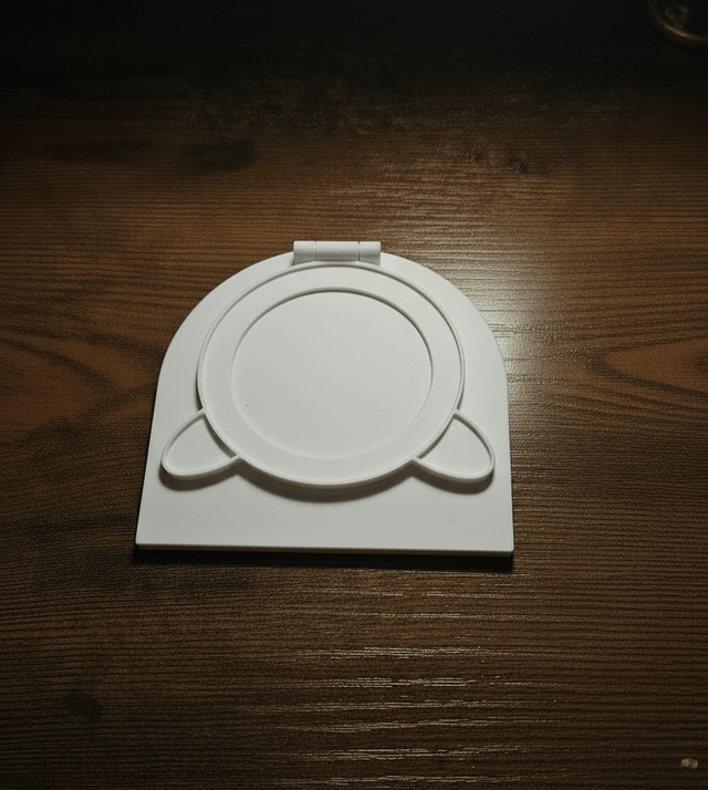 White circular object with two small horns on a wooden surface next to a decorative pen and a notebook with symbols.