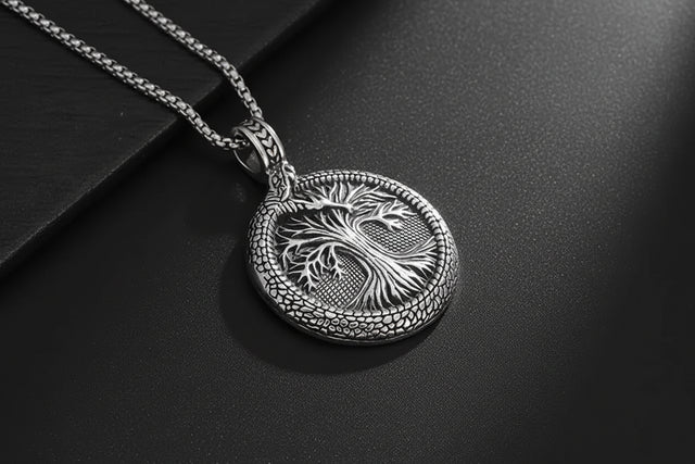 Silver tree of life pendant on a chain held in a hand against a dark background