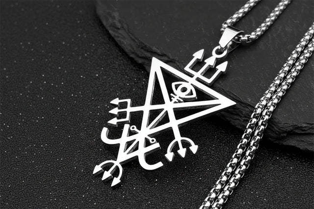 Silver pendant with intricate design on a black stone surface