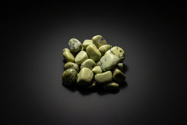 Hand holding a collection of green stones against a green mossy background