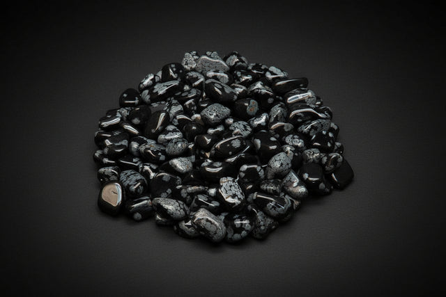 Heap of snowflake obsidian black and gray decorative stones on a white background