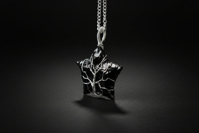 Black obsidian star-shaped pendant on a chain against a green blurred background