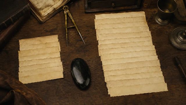 Two groups of blank parchment slips with a black scrying stone and brass dividers comparing the Enochian Calls and Aethyrs