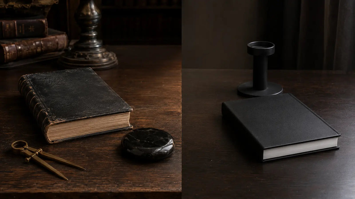 Two black books with an obsidian scrying stone, brass dividers, and candleholder arranged to compare Enochian traditions
