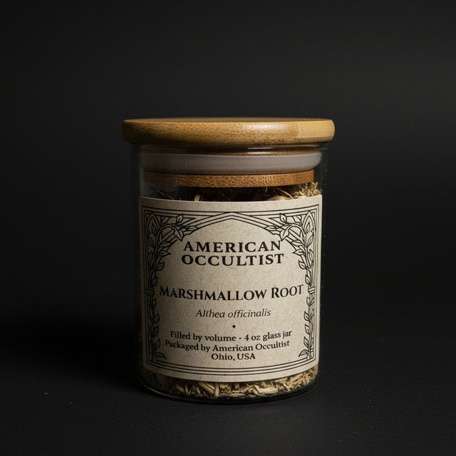 Bottle labeled 'American Occultist marshmallow root' on a marble surface with black cylindrical objects.