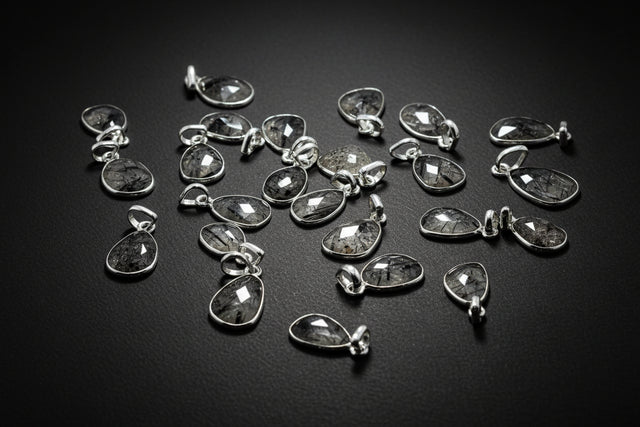 Collection of silver teardrop pendants on a black background