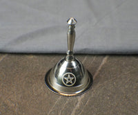 Silver bell with star design on a textured surface