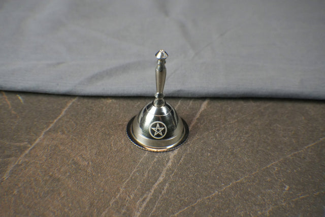 Silver bell with star design on a textured surface
