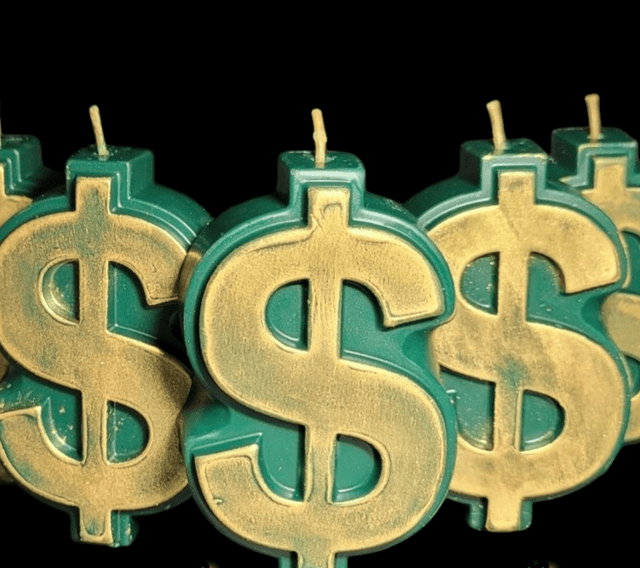 Gold dollar sign candles with green bases on a black background