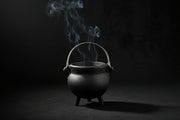 Small black cauldron with smoke on a wooden surface