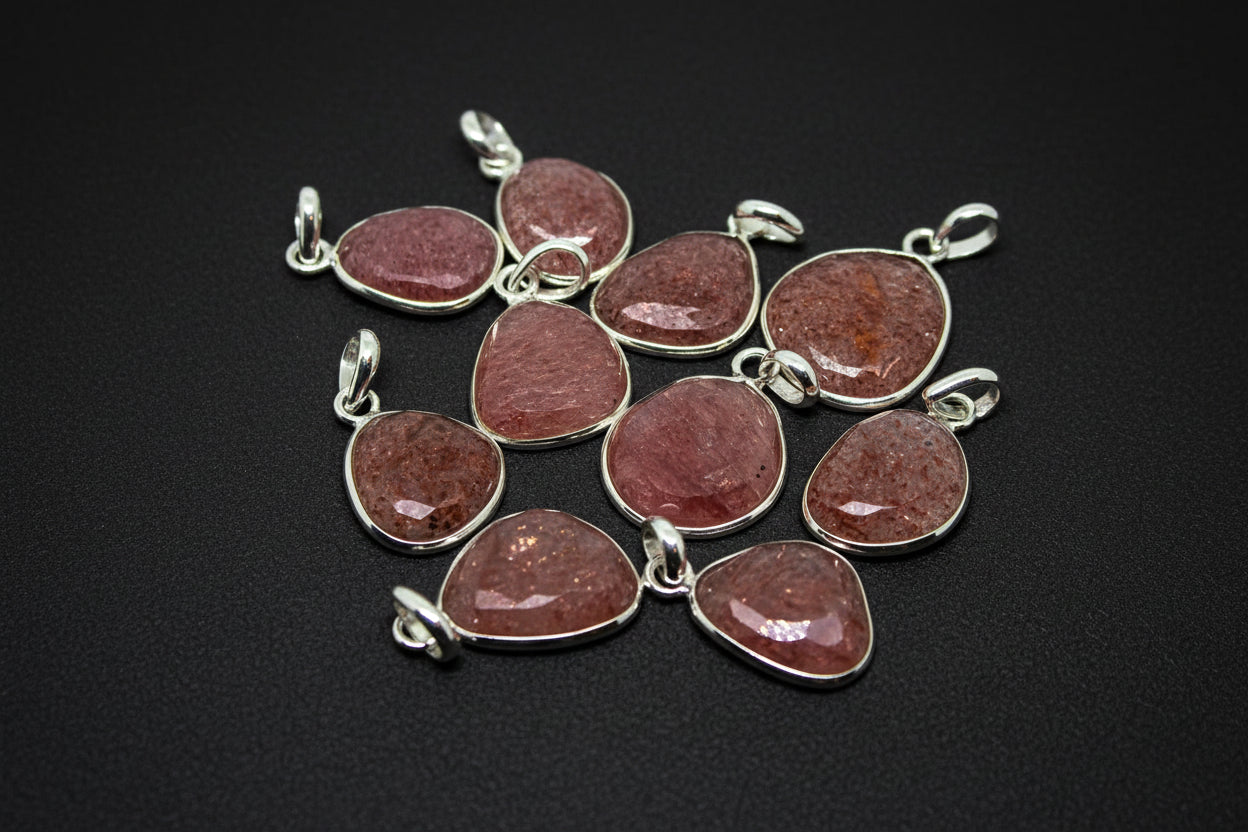 Pink stone pendants with silver settings on a black background