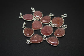 Pink stone pendants with silver settings on a black background