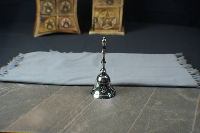 Silver bell on a textured surface with a dark background