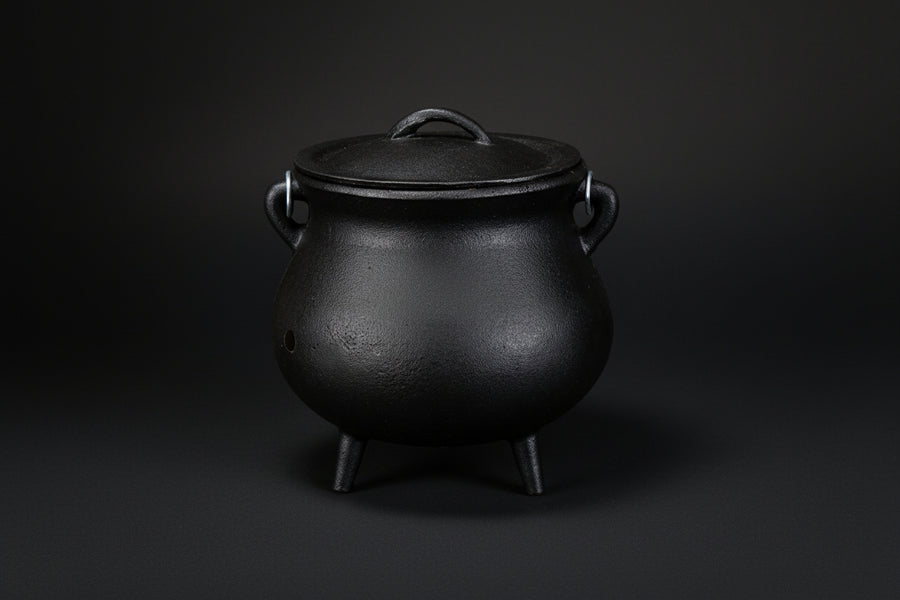Plain black cast iron cauldron with three legs and lid